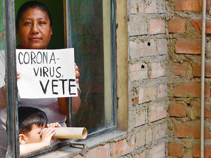 Women holding coronavirus "go-away" sign in Spanish